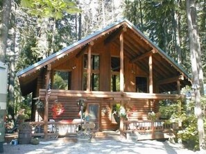 A wooden cabin with a pitched roof, large windows, and a porch area with outdoor seating. - 

Spring is here and Summer is on the way! (Ronald)