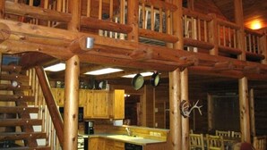 Een houten cabin met een keukenhoek, een houten trap en een eethoek.