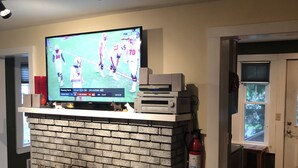 A living room with a brick fireplace, a flat-screen TV mounted above it, and a small table with a glass vase.