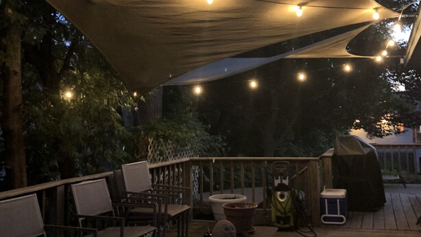 An outdoor deck with string lights, chairs, and a table.