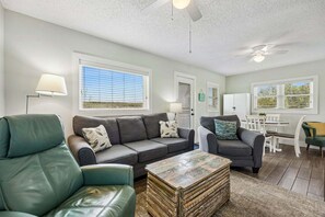 A living room with a sofa, a coffee table, and a ceiling fan.