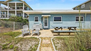 A two-story building with a covered patio area, outdoor seating, and a visible door number.