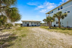 A two-story building with a front porch, a gravel driveway, and palm trees.