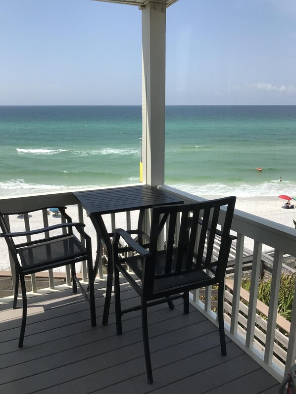 A wooden deck with a table and chairs overlooking a beach. - Gulf Front-private beach -west end unit-  sunsets from unit! August reduced!! (Seacrest)