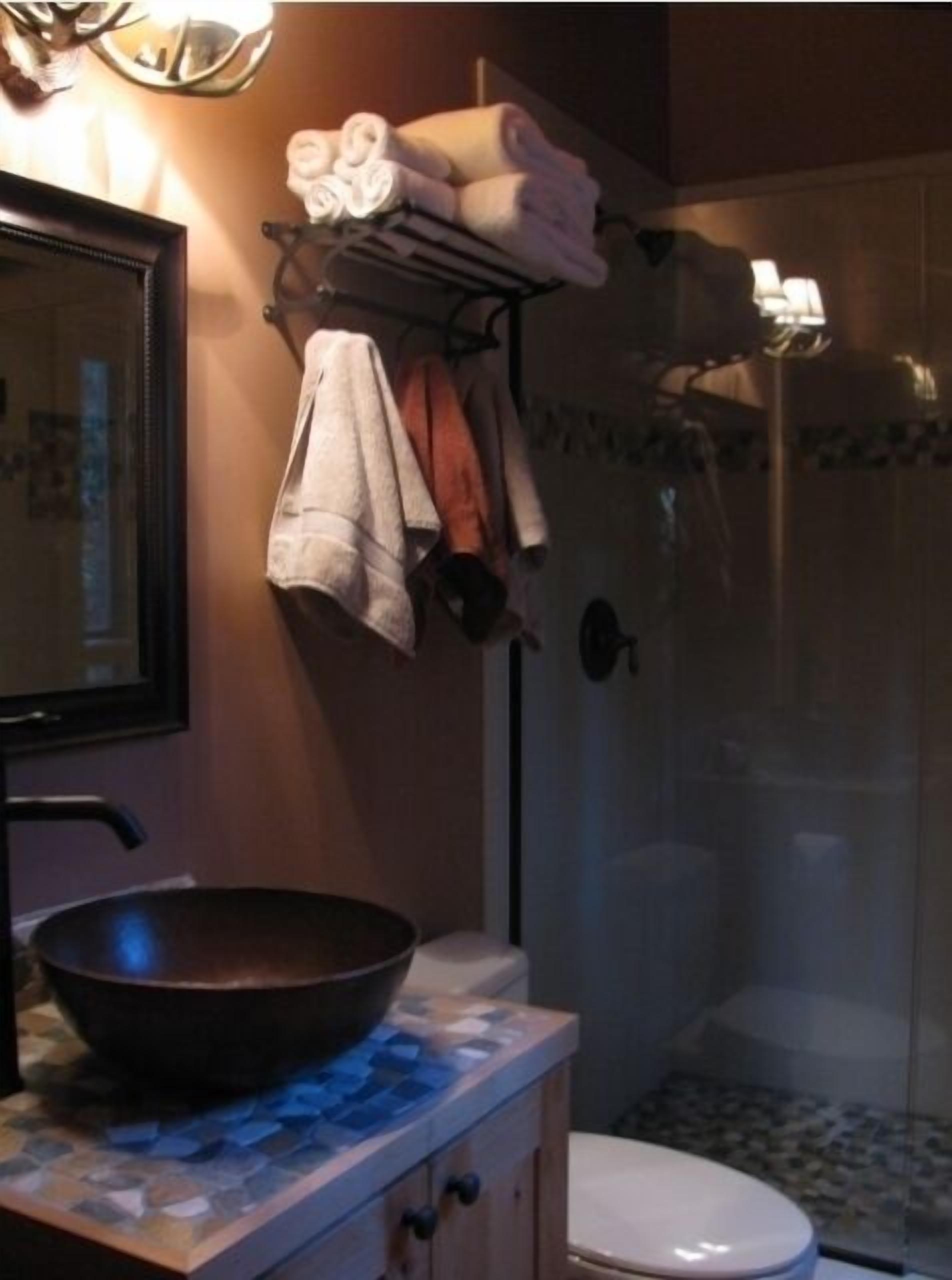 Une salle de bain équipée d’un lavabo, d’un miroir, d’un porte-serviettes et d’une douche.