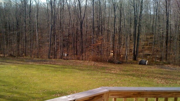 A wooden deck with a view of a grassy field and a forest in the background. - 2400sf Secluded Family Mountain House 16 Acres- 2 min to Jiminy Peak- near Lenox (Hancock)