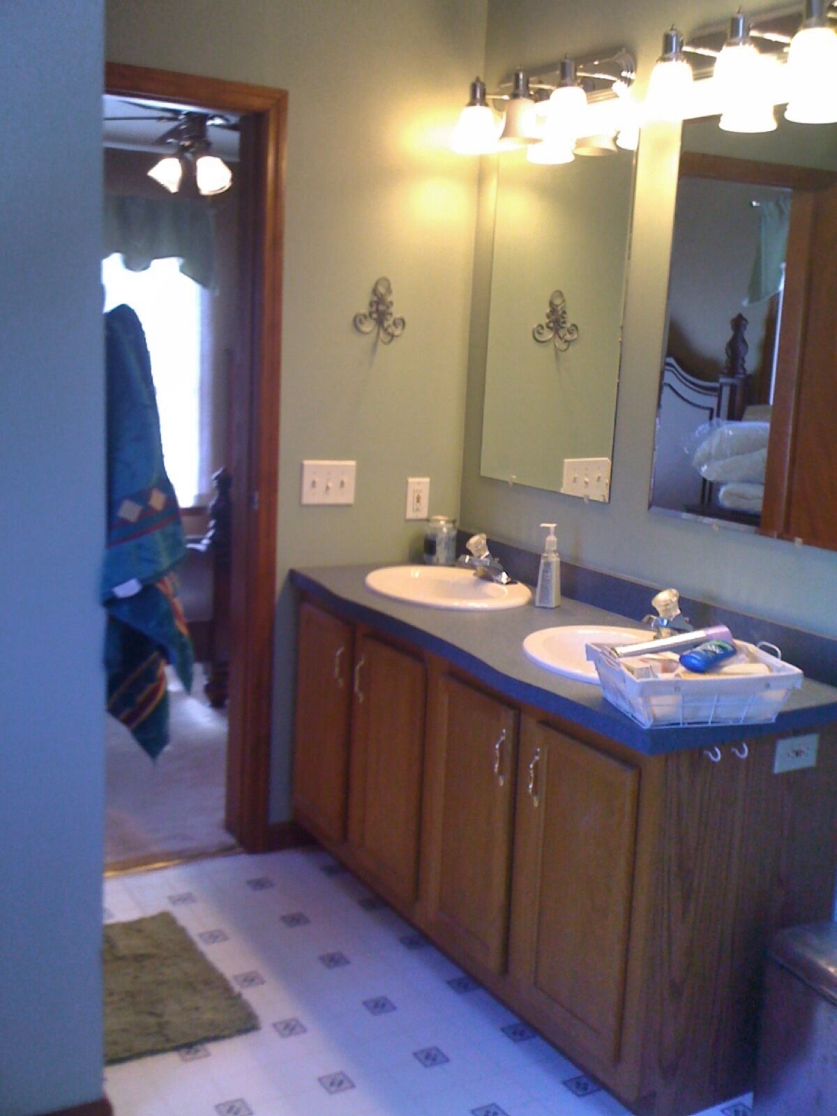 Une salle de bain avec un meuble-lavabo en bois, deux vasques, un miroir et un luminaire au plafond.