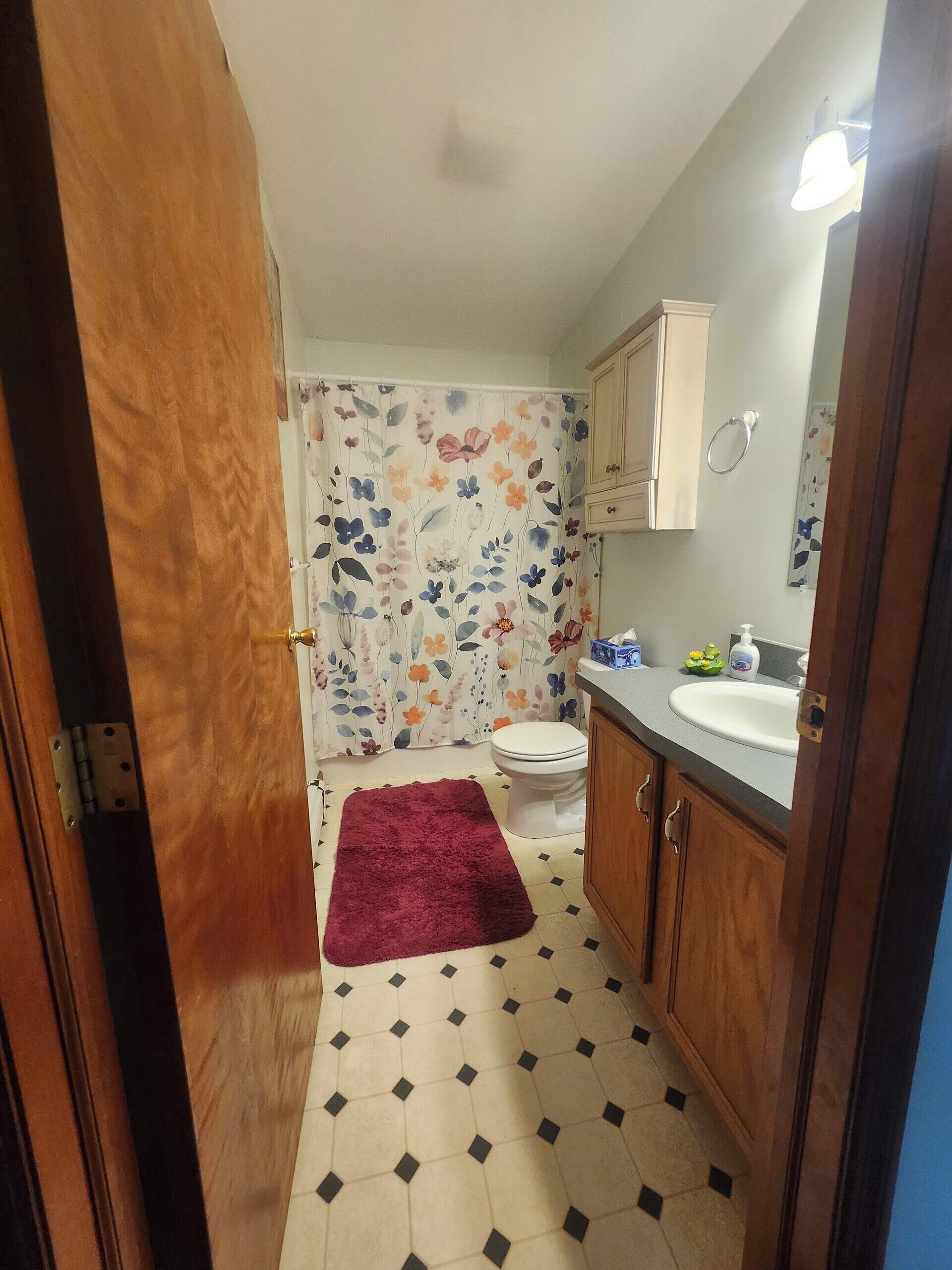 A bathroom with a toilet, sink, and wooden cabinets.