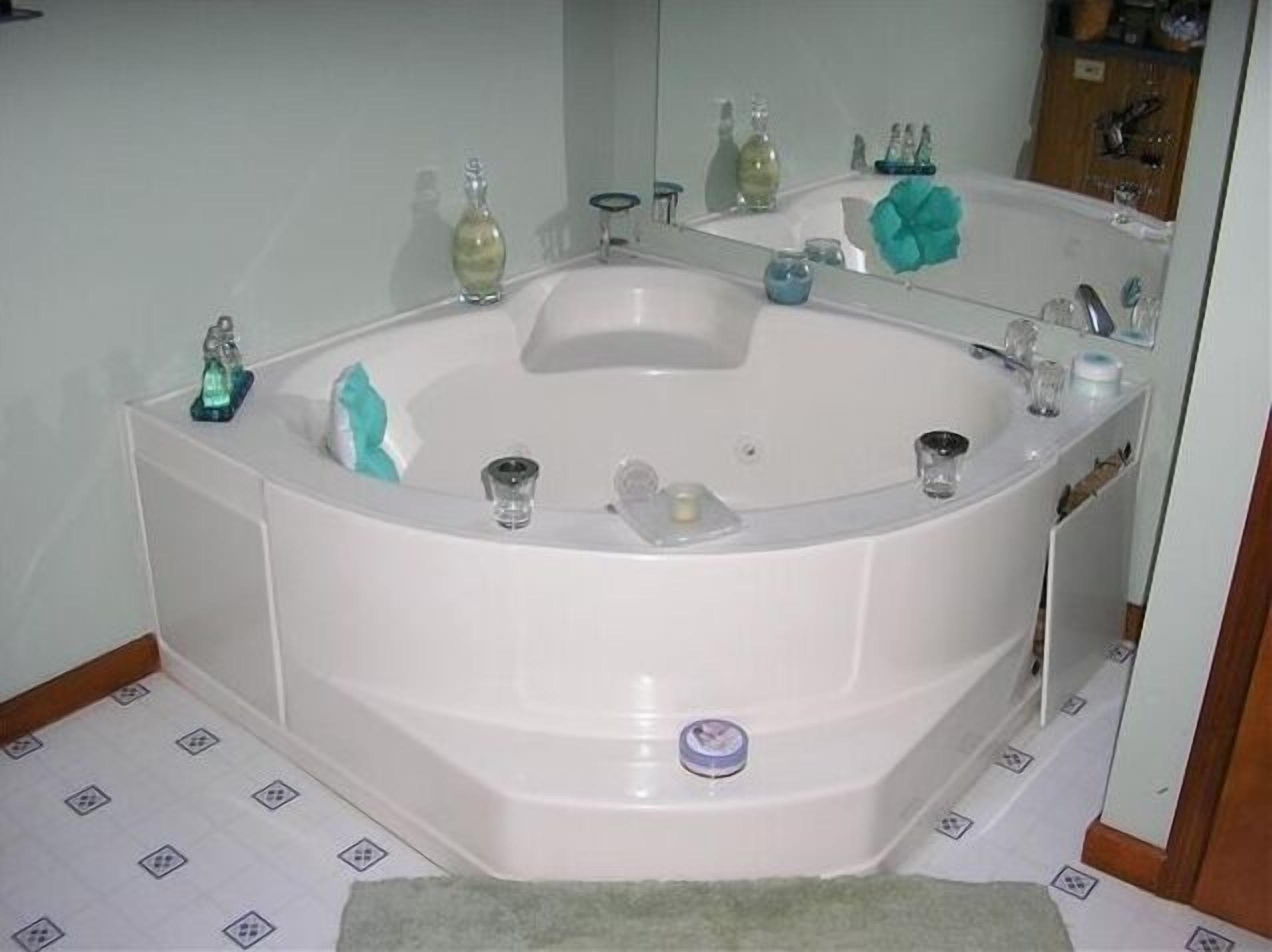 A corner bathroom with a freestanding bathtub, a mirror, and a sink.