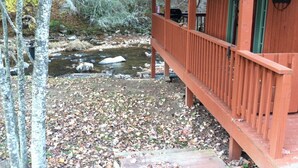 A wooden cabin with a porch overlooking a stream. - Cozy Little Cabin Located Along The Banks Of A Beautiful Trout Stream (Lansing)