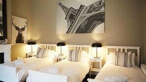 Una habitación de hotel con dos camas, una chimenea y obras de arte en las paredes.