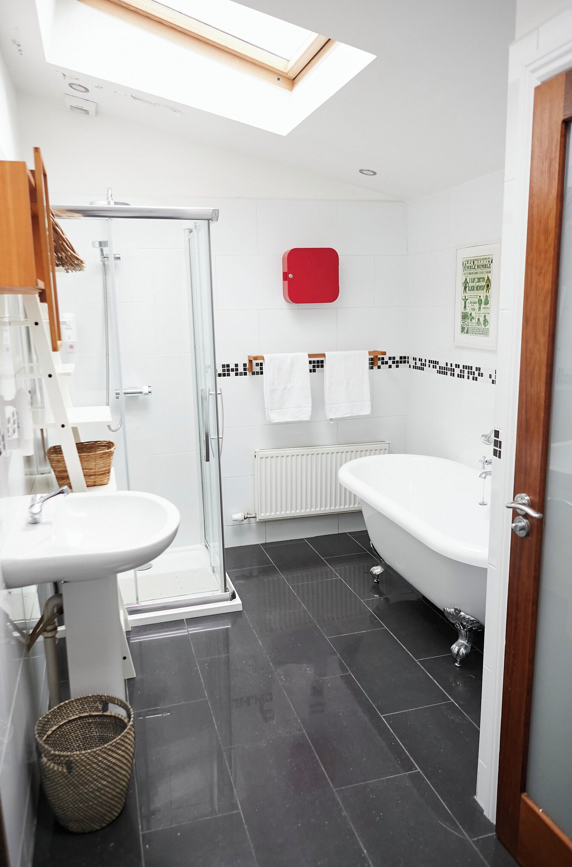 Un baño moderno con cabina de ducha de vidrio, un lavabo blanco, una bañera independiente y suelo de baldosas.