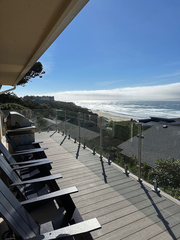 Un balcon avec vue sur l’océan, un coin salon et un bâtiment en arrière-plan.