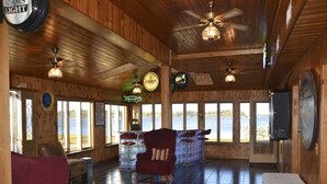 A wooden interior with a large window, a ceiling fan, and a bar area with stools.