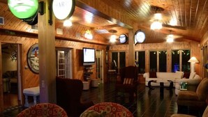 A cozy, wooden-floored living room with a television, seating area, and a turtle on a table.