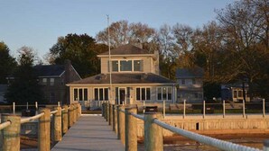 A wooden boardwalk leading to a two-story building with a covered entrance and windows.