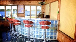 A bar area with four stools, a counter, and a view of the lake.