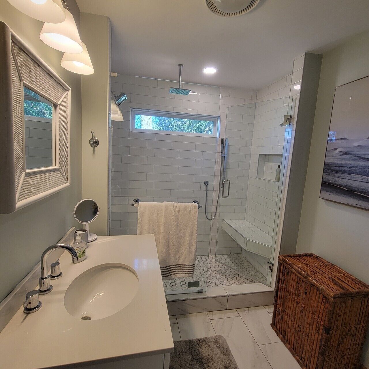 A modern bathroom with a white sink, mirror, and shower.