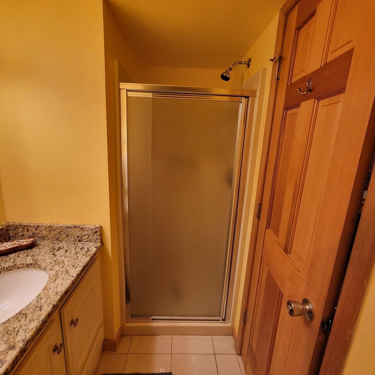 A bathroom with a shower, a sink, and wooden cabinets.