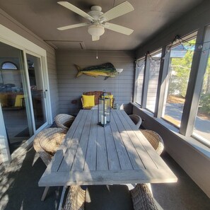 Relax outdoors with a covered patio featuring a table and wicker chairs, ceiling fan, and a window.