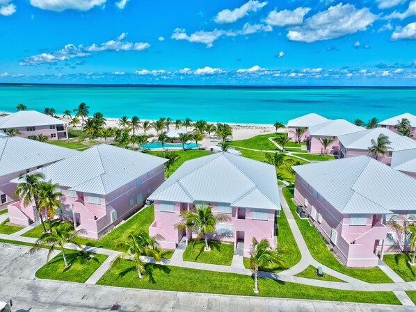 Ein Resort mit mehreren rosa Gebäuden, einem Pool und Blick auf den Strand.