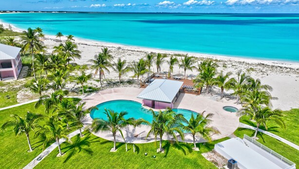 Un resort con piscina, palmeras y una playa.