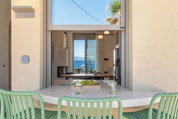 A dining area with a table, chairs, and a view of the sea.