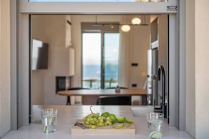A kitchen with a cutting board holding grapes and limes, and two glasses of water.