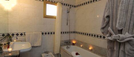 A bathroom with a bathtub, a bidet, a sink, and a window.