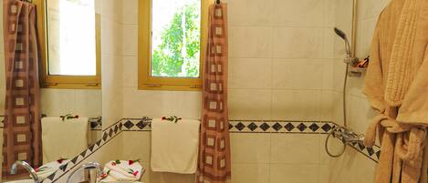 A bathroom with a sink, mirror, shower, and towel rack.
