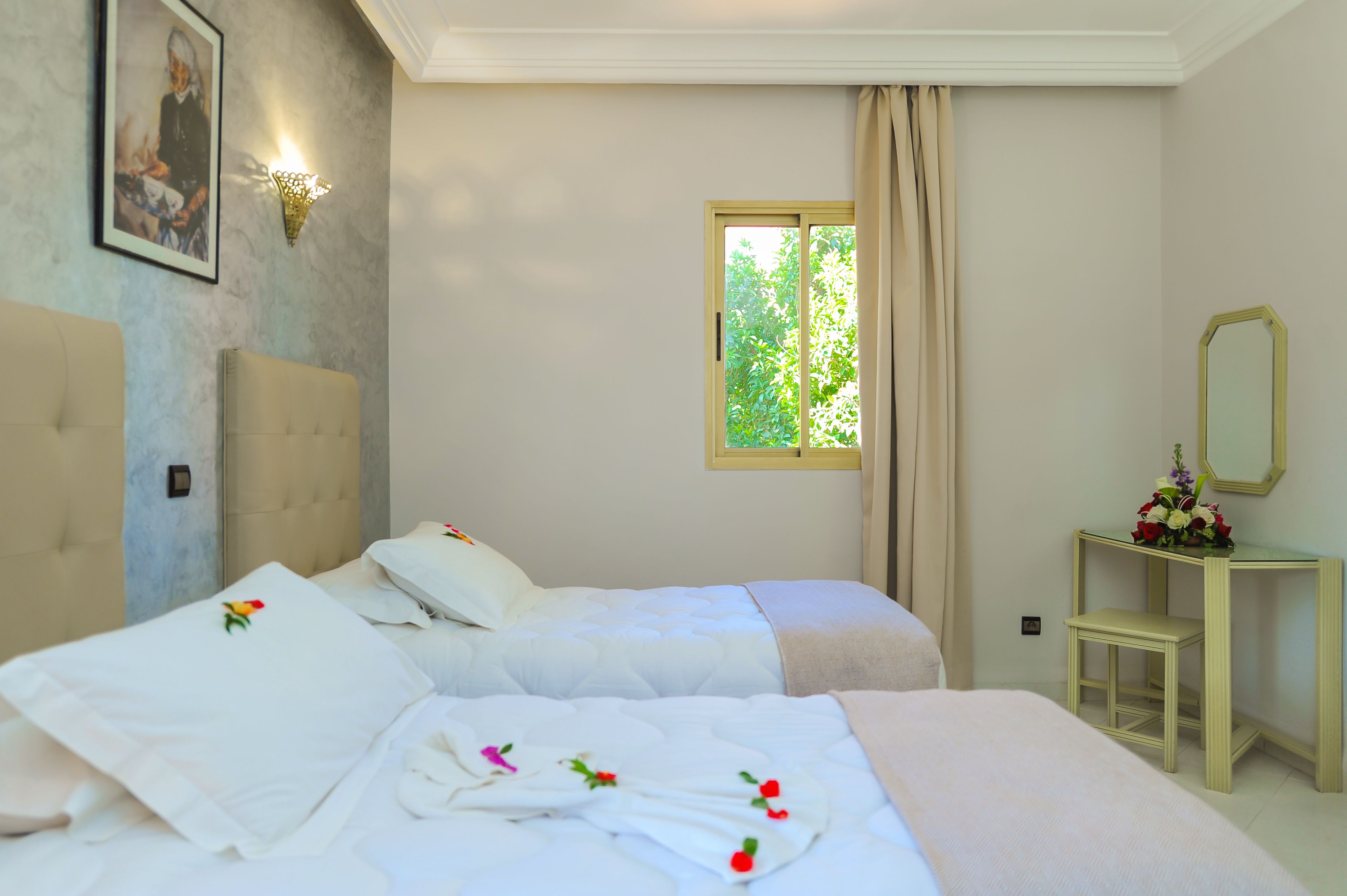 Una habitación de hotel con cama, mesita de noche, espejo y ventana con cortinas.