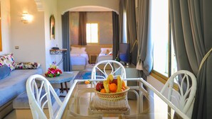 Una habitación de hotel con una mesa de comedor, un sofá, una cama y una ventana con cortinas.