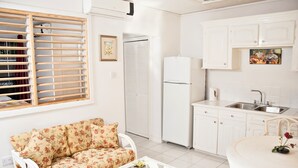 Eine kompakte Küche mit weißen Schränken, einem weißen Kühlschrank und einem Essbereich mit Tisch und Stühlen.