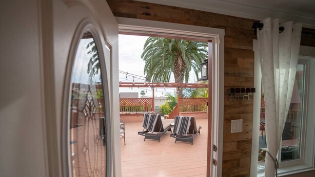 An open door to a patio with two lounge chairs and a palm tree. - Walk everywhere; Beach 300 steps (Laguna Beach)