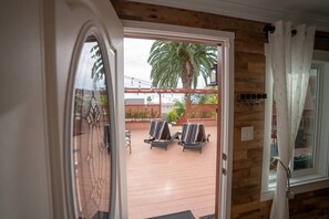 An open door to a patio with two lounge chairs and a palm tree. - Walk everywhere; Beach 300 steps (Laguna Beach)