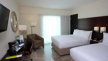 A hotel room with two beds, a desk with a coffee maker, a chair, and a TV.