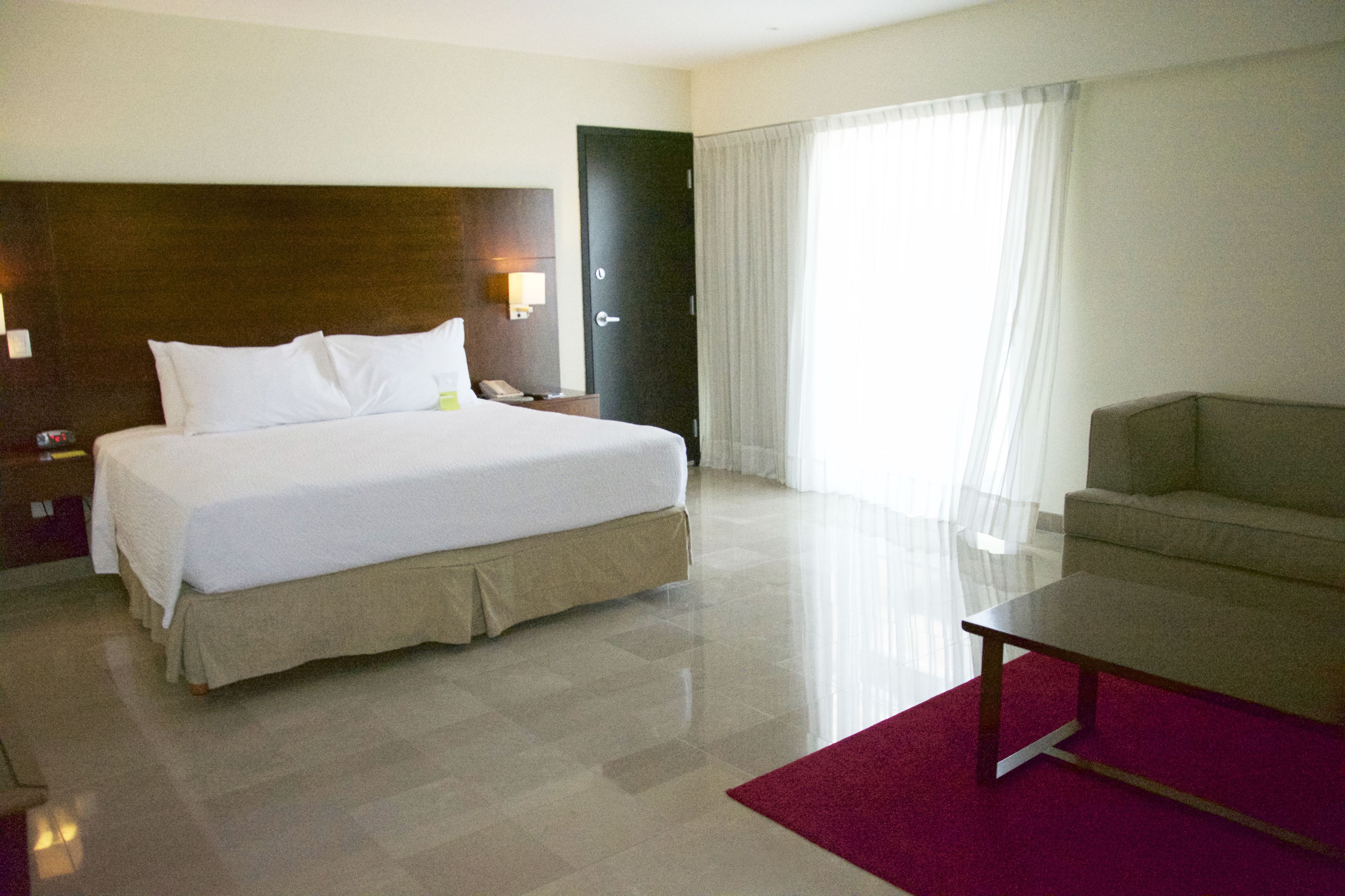 Una habitación de hotel con una cama grande, un escritorio, una silla y una puerta.
