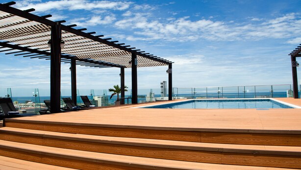 A rooftop pool area with wooden steps, lounge chairs, and a pergola structure. - Four Points by Sheraton Veracruz (Boca del Río)
