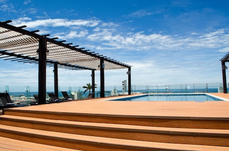 Una piscina al aire libre, sillones reclinables de piscina