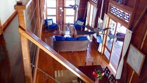 A wooden interior with a staircase, a sofa, a dining table, and a ceiling fan. - Casa Del Mar (Tierra Oscura)