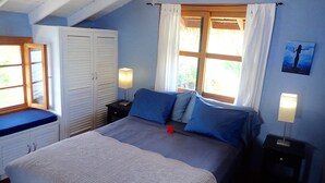 A bedroom with a bed, a nightstand, a wardrobe, and a window with curtains. - Casa Del Mar (Tierra Oscura)