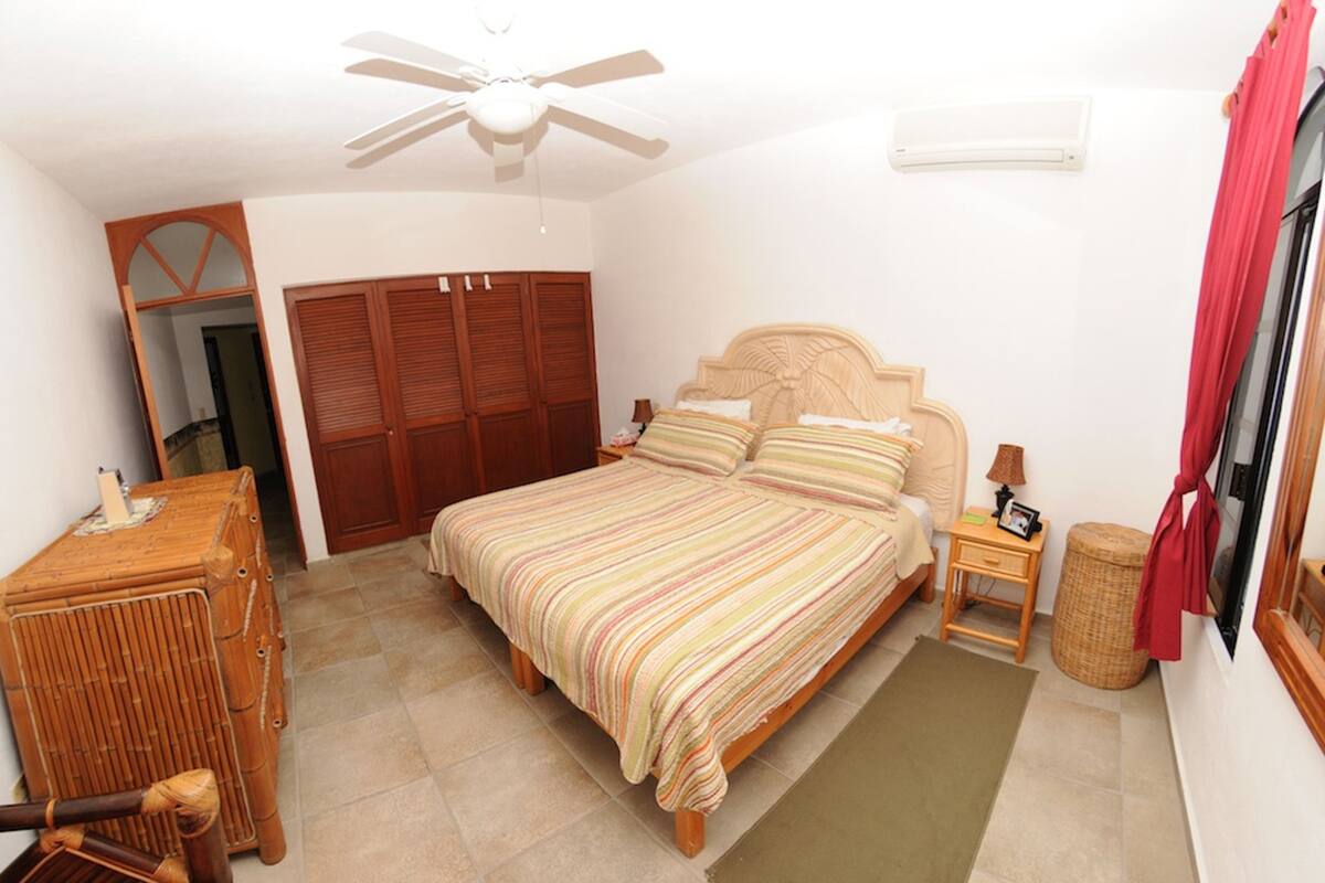 Ein Schlafzimmer mit Bett, Kleiderschrank, Nachttisch und Deckenventilator.