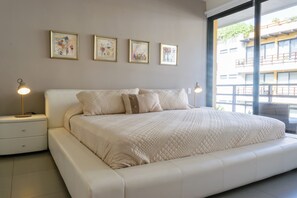 Un dormitorio moderno con una cama grande, mesitas de noche y una obra de arte en la pared.
