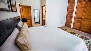 Een netjes opgemaakt bed in een hotelkamer met een houten hoofdeinde, een nachtkastje met een lamp en een grote garderobe.