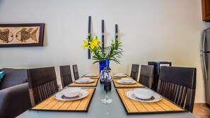 Een eettafel gedekt voor zes personen, met plaatszetters, kommen en een vaas met bloemen.