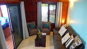 A living area with a sofa set, a coffee table with a vase, and a sliding glass door leading to an outdoor area.