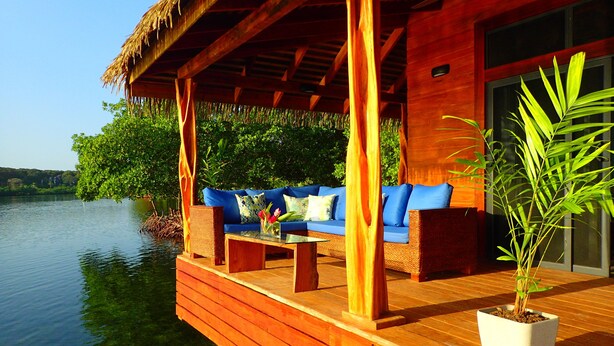 A wooden deck with a sofa and a table, overlooking a body of water.