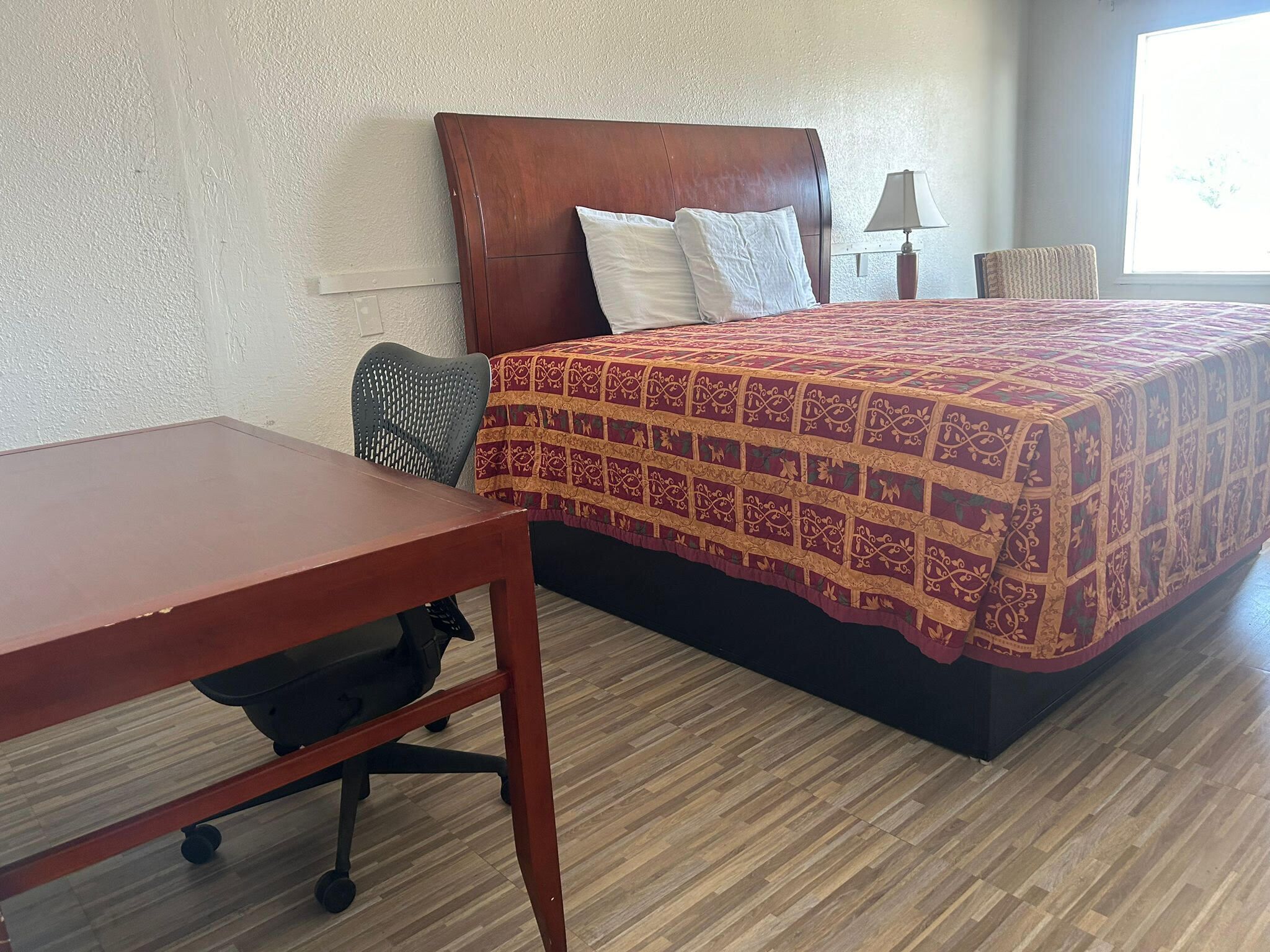 Una habitación de hotel con una cama de madera, un escritorio y una silla.