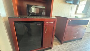 A compact kitchen with a microwave, a refrigerator, and a small cabinet. - Quest Inn (Weatherford)
