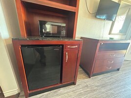 Cocina compacta con microondas, refrigerador y un mueble pequeño.